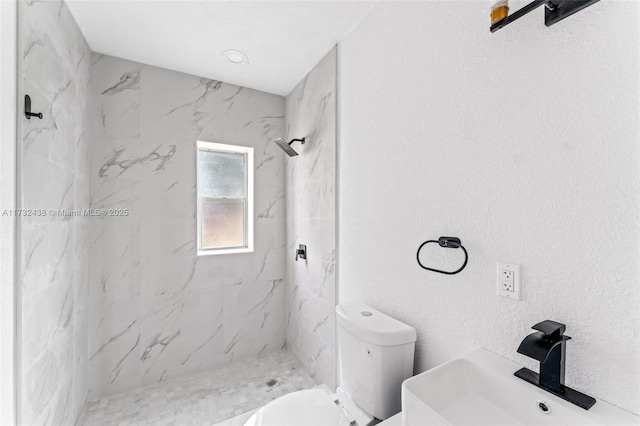 bathroom featuring toilet, sink, and a tile shower