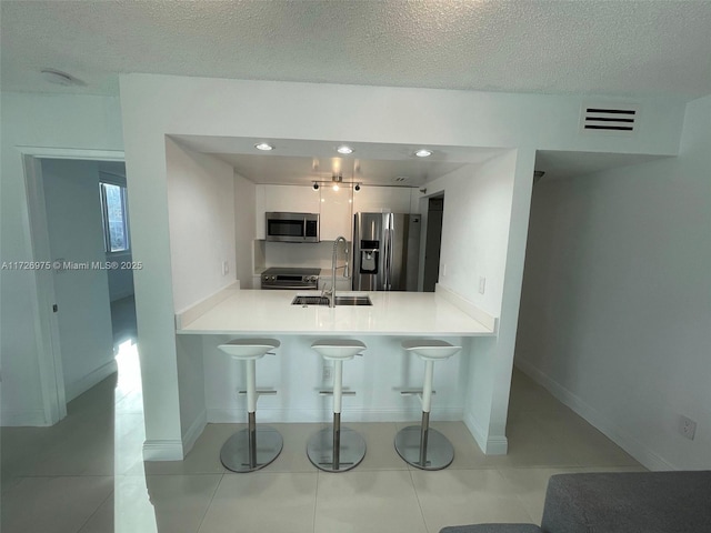 kitchen featuring visible vents, appliances with stainless steel finishes, a breakfast bar, a peninsula, and a sink