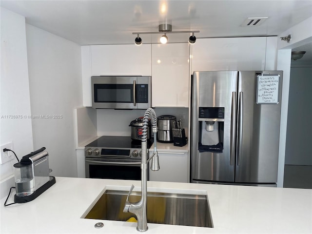 kitchen with white cabinets, modern cabinets, stainless steel appliances, and light countertops