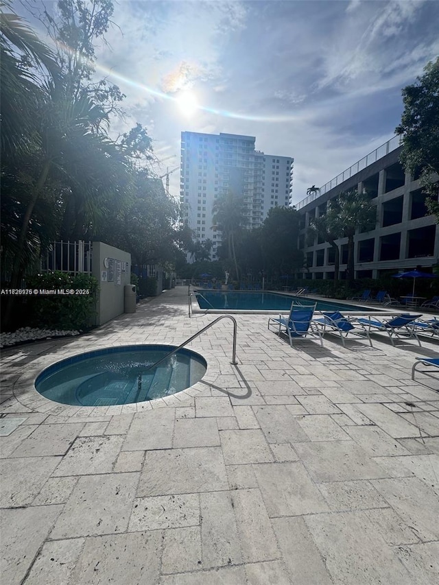 community pool featuring a community hot tub, a patio area, and a city view