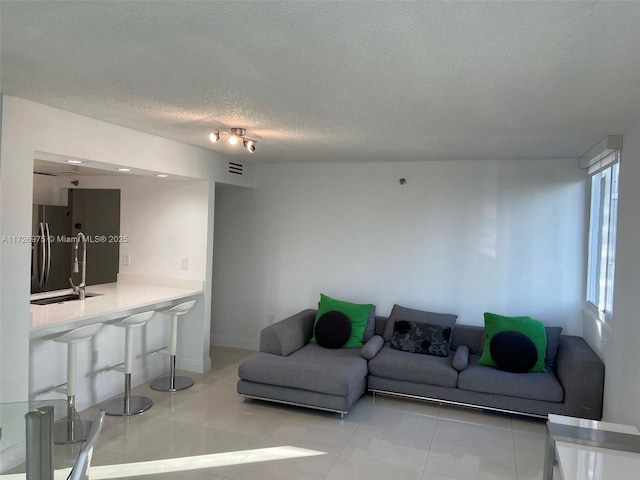 living area featuring light tile patterned floors, baseboards, and a textured ceiling