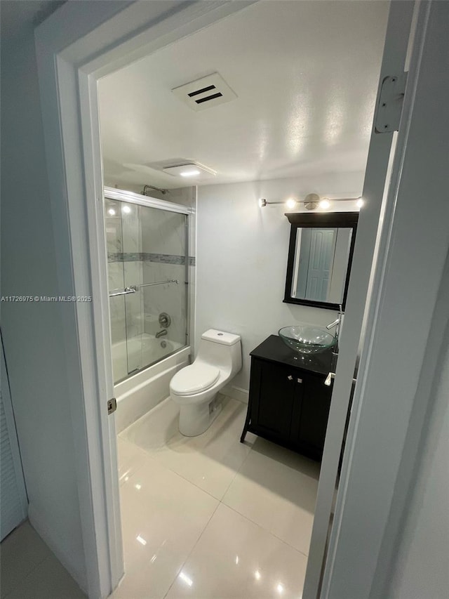 bathroom with visible vents, bath / shower combo with glass door, toilet, tile patterned flooring, and vanity