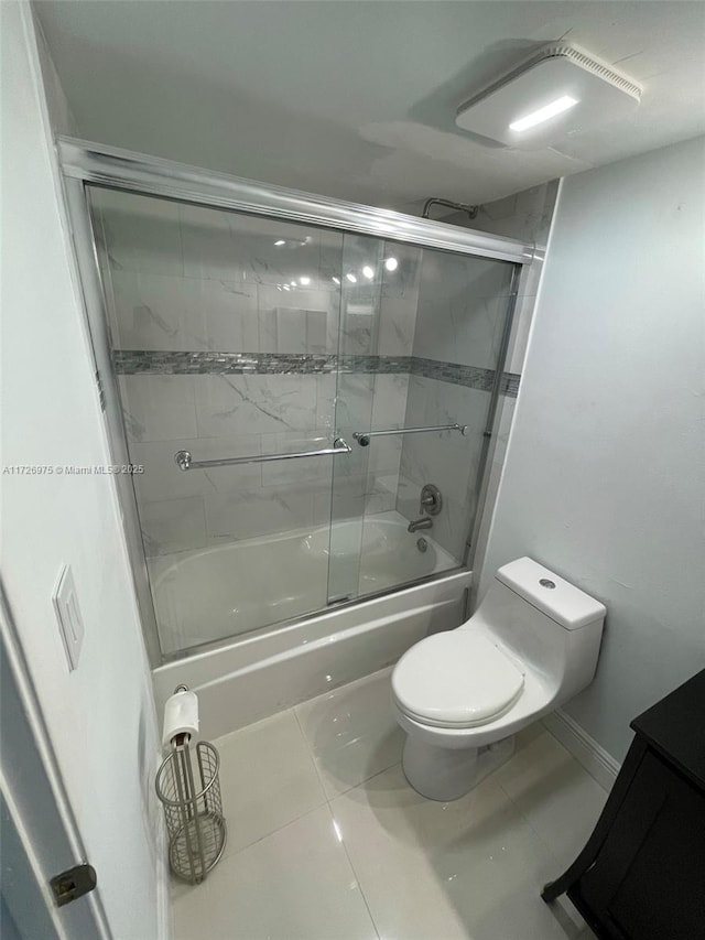 bathroom with tile patterned flooring, baseboards, toilet, and bath / shower combo with glass door