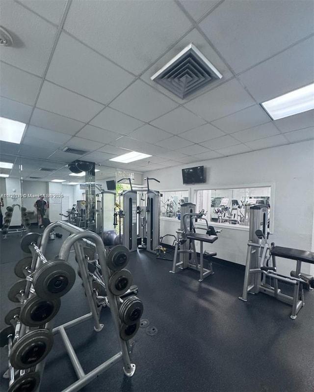 exercise room featuring plenty of natural light, a drop ceiling, and visible vents