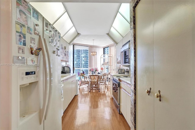 kitchen featuring pendant lighting, white cabinets, a notable chandelier, stainless steel appliances, and light wood-type flooring