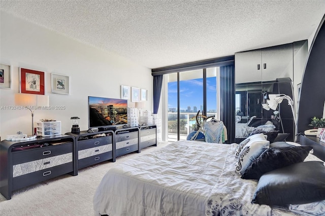 carpeted bedroom with access to outside, a textured ceiling, and a wall of windows