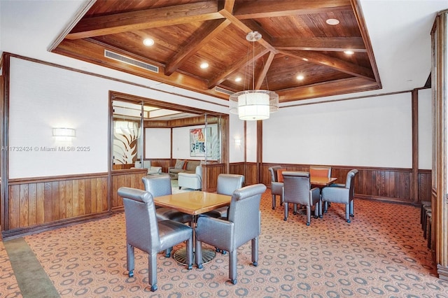 carpeted dining space featuring beam ceiling, wood ceiling, wooden walls, and ornamental molding