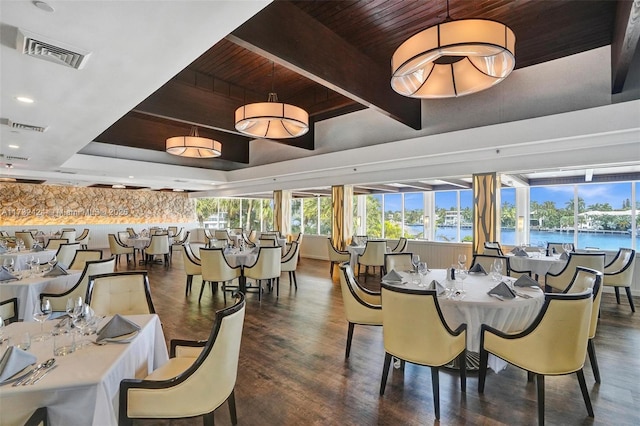 dining space with wood ceiling, beam ceiling, a water view, dark hardwood / wood-style flooring, and a raised ceiling