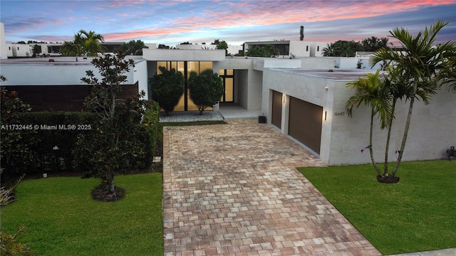 view of front of home with a garage and a lawn