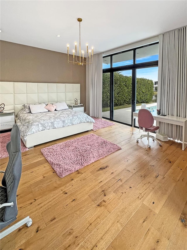 bedroom with an inviting chandelier, wood-type flooring, floor to ceiling windows, and access to outside