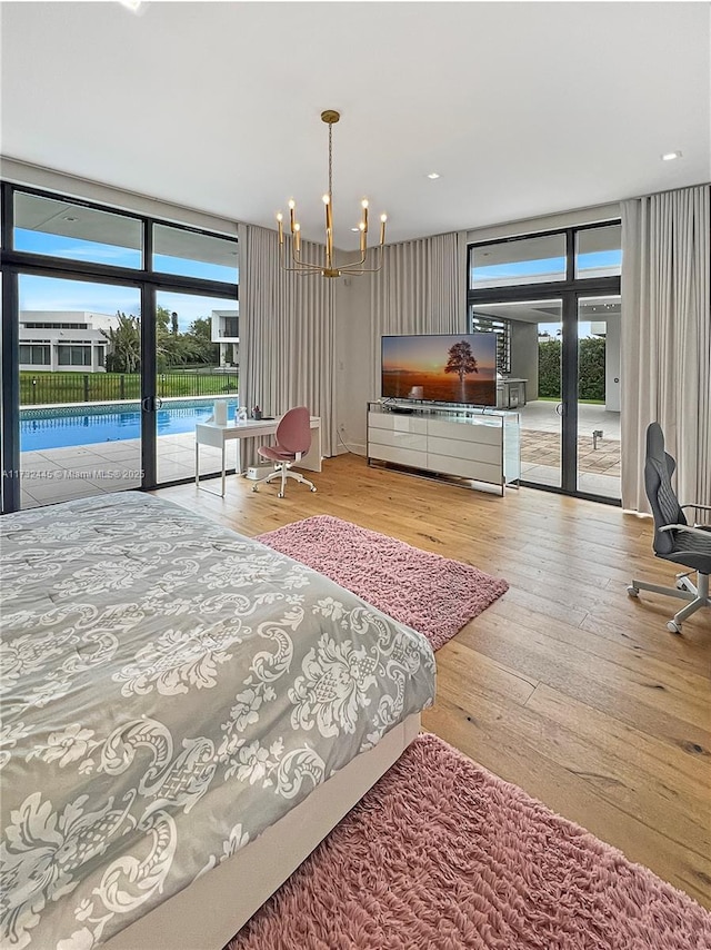 bedroom featuring expansive windows, access to outside, a notable chandelier, and light wood-type flooring