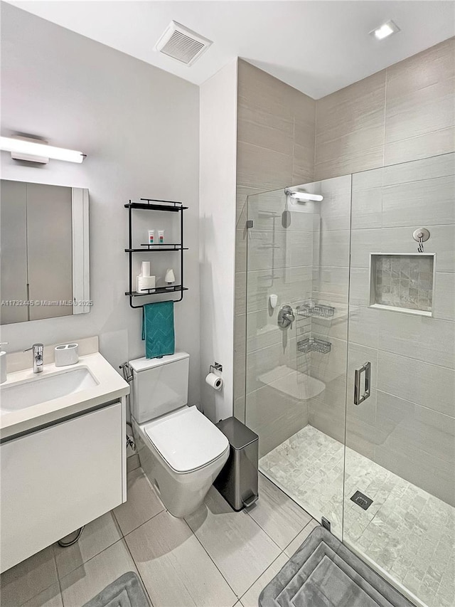 bathroom with tile patterned flooring, vanity, an enclosed shower, and toilet