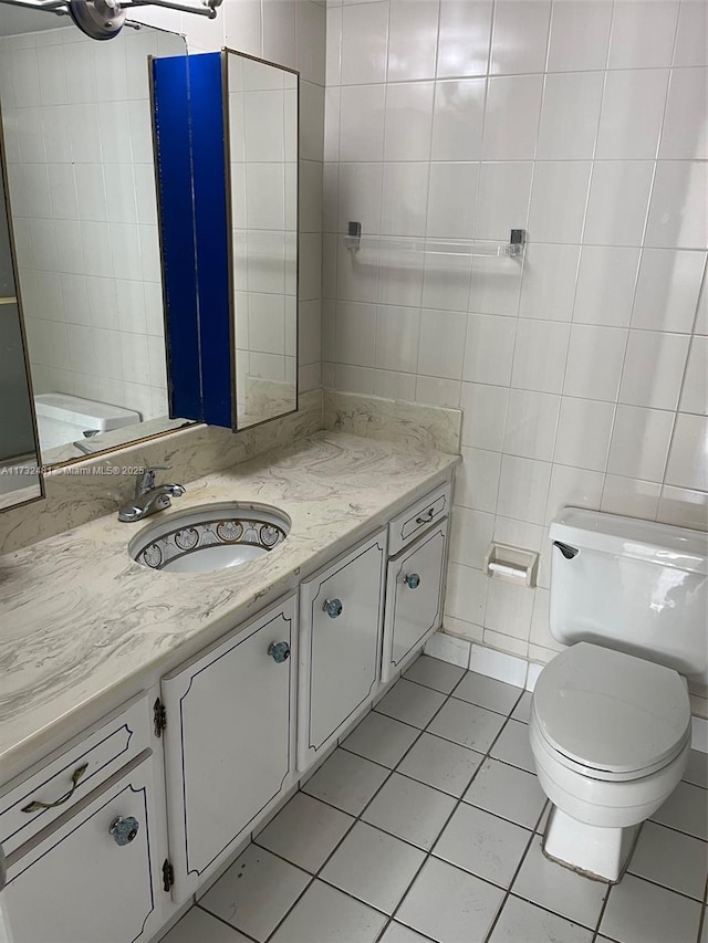 bathroom featuring vanity, tile walls, tile patterned floors, and toilet