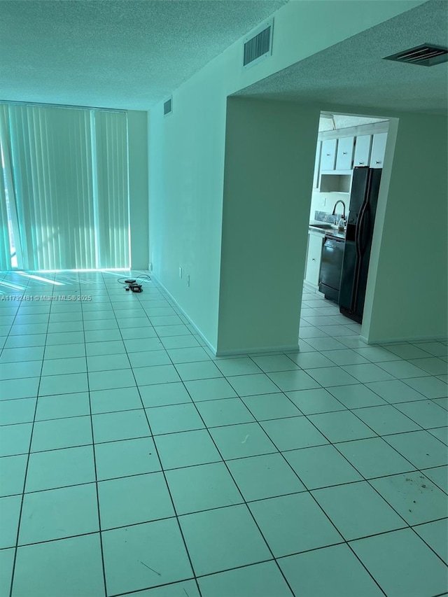 empty room with light tile patterned flooring, sink, and a textured ceiling