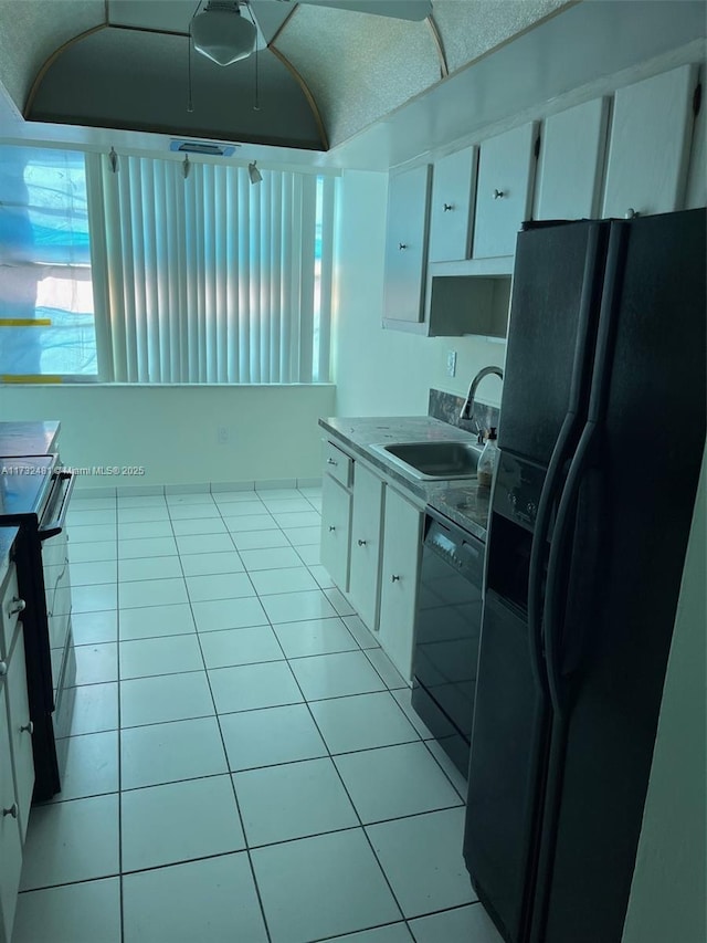 kitchen with light tile patterned flooring, sink, white cabinets, and black appliances