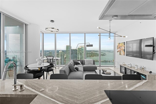 kitchen with expansive windows, island exhaust hood, white cabinets, and black electric cooktop