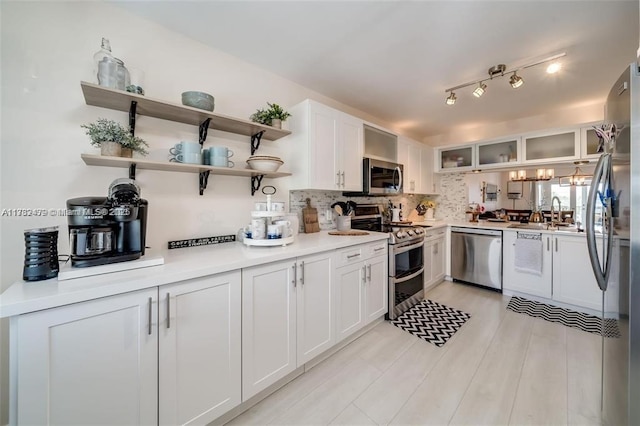 kitchen with backsplash, appliances with stainless steel finishes, sink, and white cabinets