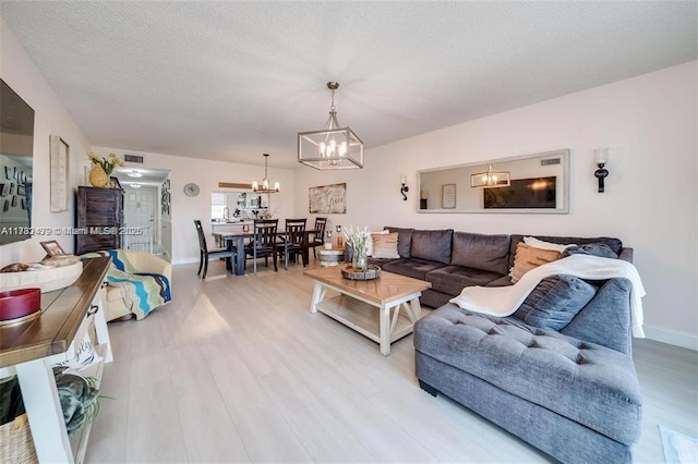 living room featuring an inviting chandelier, hardwood / wood-style flooring, and a textured ceiling