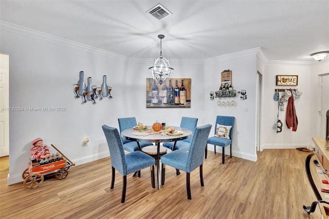 dining area with crown molding, light hardwood / wood-style flooring, and a chandelier