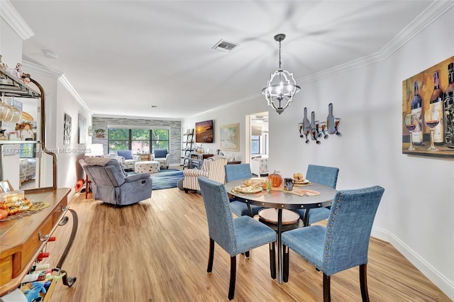 dining area with ornamental molding, a chandelier, and light hardwood / wood-style flooring