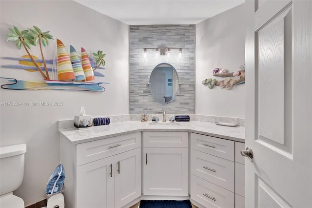 bathroom with vanity, decorative backsplash, and toilet