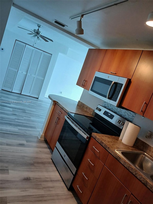 kitchen with sink, light hardwood / wood-style flooring, ceiling fan, stainless steel appliances, and track lighting