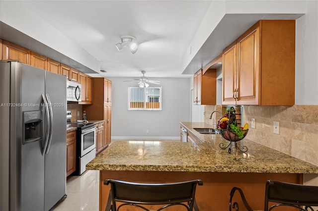 kitchen featuring sink, backsplash, a kitchen bar, kitchen peninsula, and stainless steel appliances