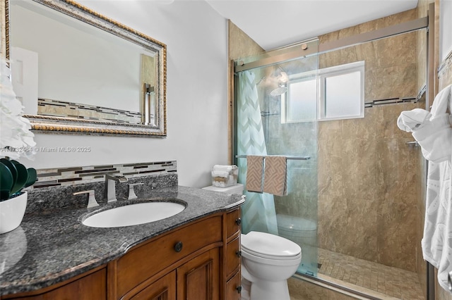 bathroom featuring vanity, a shower with door, and toilet