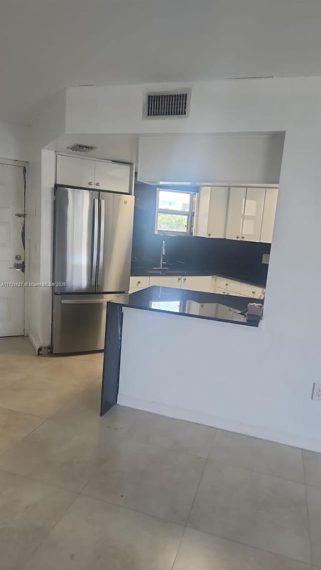 kitchen with stainless steel refrigerator, sink, and white cabinets