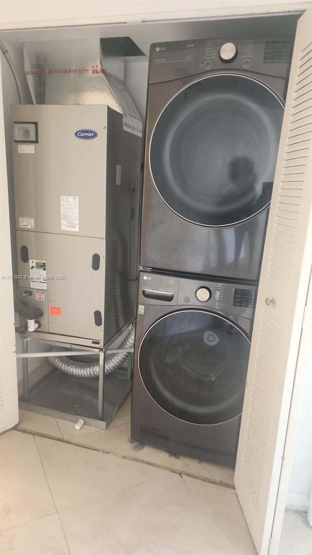 laundry area with stacked washer and dryer, heating unit, and tile patterned flooring