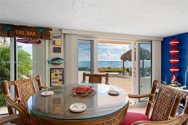 dining space with a water view and a textured ceiling