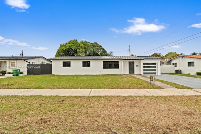 ranch-style house with a garage, a front yard, and central AC unit