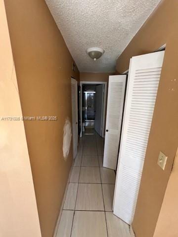 corridor with light tile patterned floors and a textured ceiling