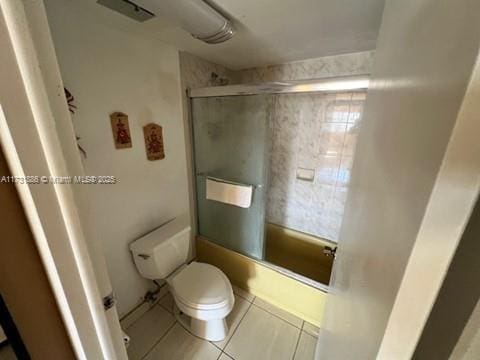 bathroom featuring tile patterned floors, enclosed tub / shower combo, and toilet