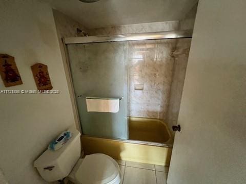 bathroom featuring combined bath / shower with glass door, tile patterned floors, and toilet