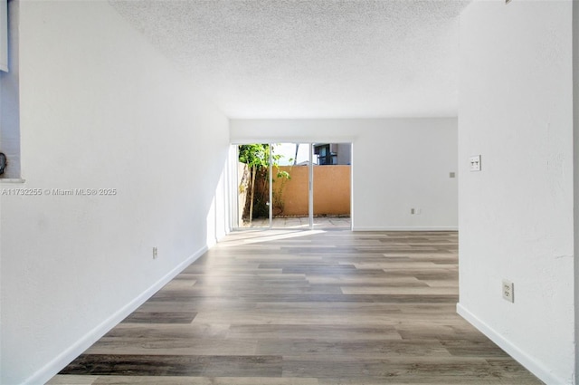 unfurnished room with wood-type flooring and a textured ceiling