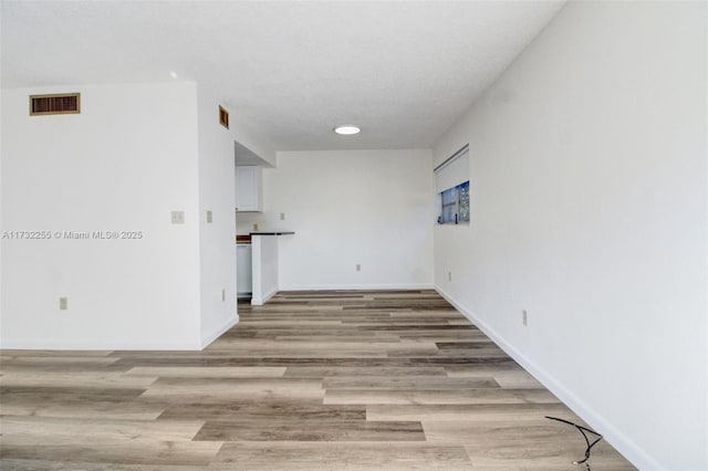 interior space with light wood-type flooring, visible vents, and baseboards