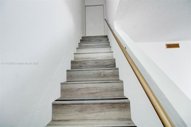 staircase featuring a textured ceiling and visible vents