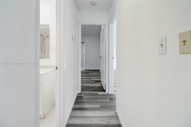 hallway featuring light wood finished floors and baseboards