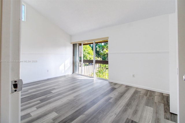 empty room featuring vaulted ceiling, wood finished floors, and baseboards