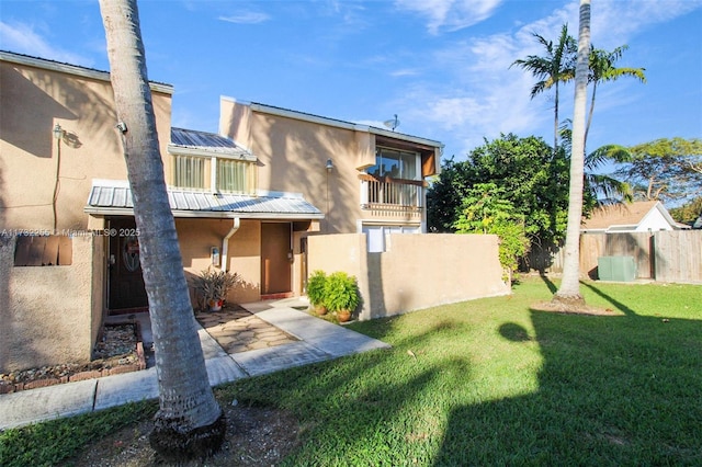 view of front of house featuring a balcony, a patio area, and a front lawn