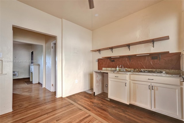 bar with white cabinetry, sink, light stone counters, and dark hardwood / wood-style flooring