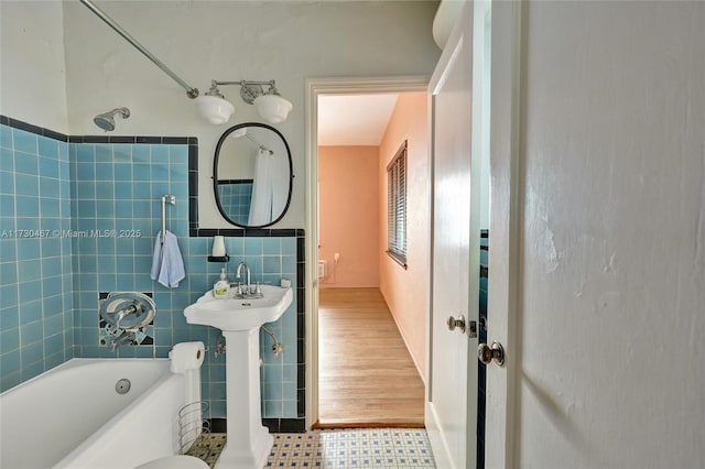 full bathroom with tiled shower / bath combo, sink, tile walls, and toilet