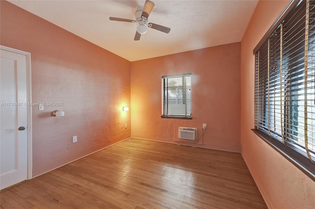 spare room featuring ceiling fan, a wall mounted AC, and light wood-type flooring