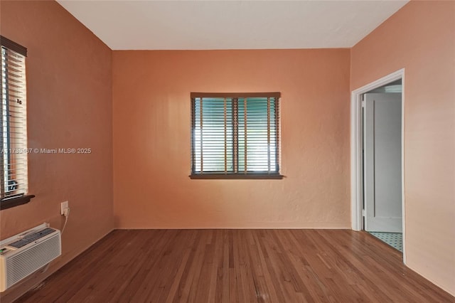 unfurnished room with hardwood / wood-style flooring and a wall unit AC