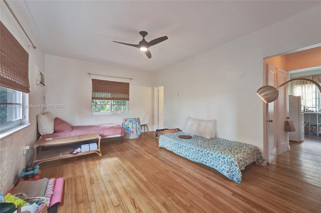 bedroom featuring ceiling fan, hardwood / wood-style floors, and multiple windows