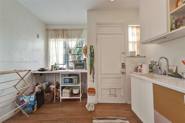 kitchen with white cabinetry, sink, and hardwood / wood-style floors