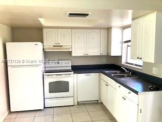 kitchen with light tile patterned flooring, sink, white cabinets, and white appliances