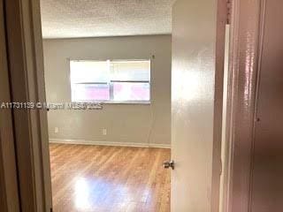 unfurnished room with a textured ceiling and light wood-type flooring