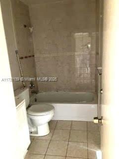 bathroom featuring tile patterned flooring, tiled shower / bath, and toilet